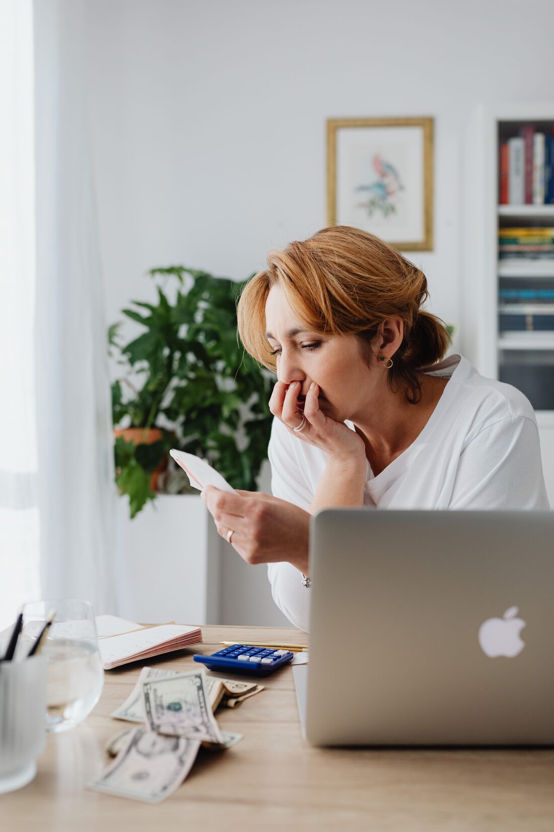 A working professional at home, worn down while reviewing bills and messages